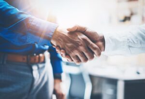 Close up view of business partnership handshake.Concept two businessman handshaking process.Successful deal after great meeting.Horizontal, flare effect, blurred background